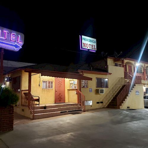 A brightly lit motel at night with a neon 